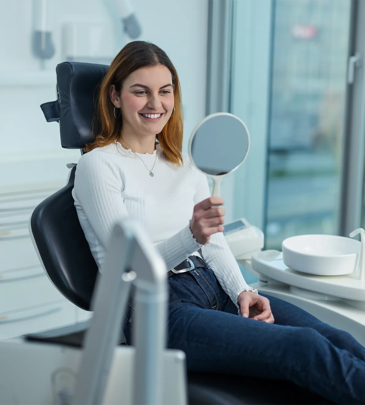 Patientin im Behandlungsstuhl mit Handspiegel — Symbolbild